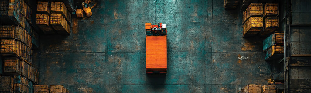Forklift Safety and Efficiency for a Fortune 500 Automotive Manufacturer 1 Aerial view of a forklift operating alone in a large warehouse aisle between stacked crates representing forklift pedestrian safety and fleet tracking challenges in manufacturing facilities