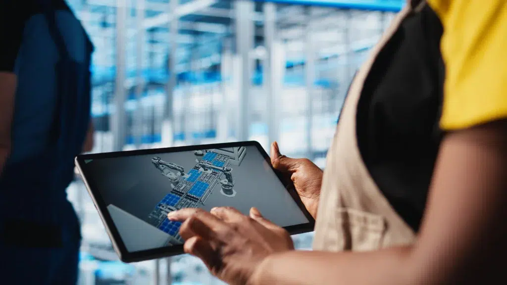 Active RFID Tags: How They Work, Key Differences, and When to Use Them 2 Smart factory engineer reviewing robotic machine design on a tablet in a manufacturing facility representing active RFID and RTLS-powered operational visibility in industrial environments