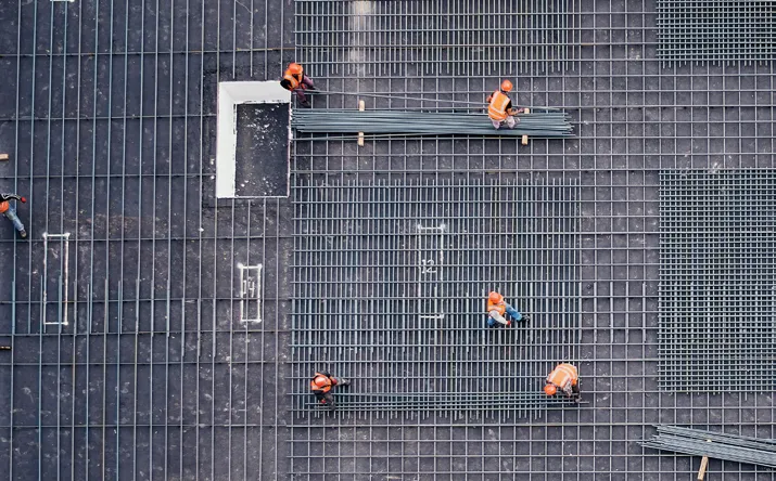 How RTLS Delivered $2.8M in Annual Savings for a Leading Global EPC Provider 2 Construction workers on a steel grid structure at a large fabrication yard