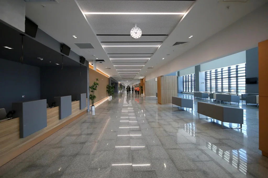 RTLS in Healthcare: Real-World Case Studies in Patient Safety, Staff Protection, and Asset Management 10 Long modern hospital corridor with staff walking in a large healthcare campus