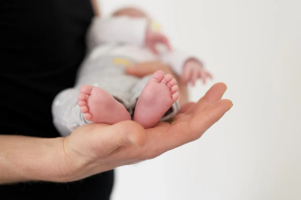 RTLS in Healthcare: Real-World Case Studies in Patient Safety, Staff Protection, and Asset Management 11 Newborn baby feet resting in a caregiver's hands in a hospital setting
