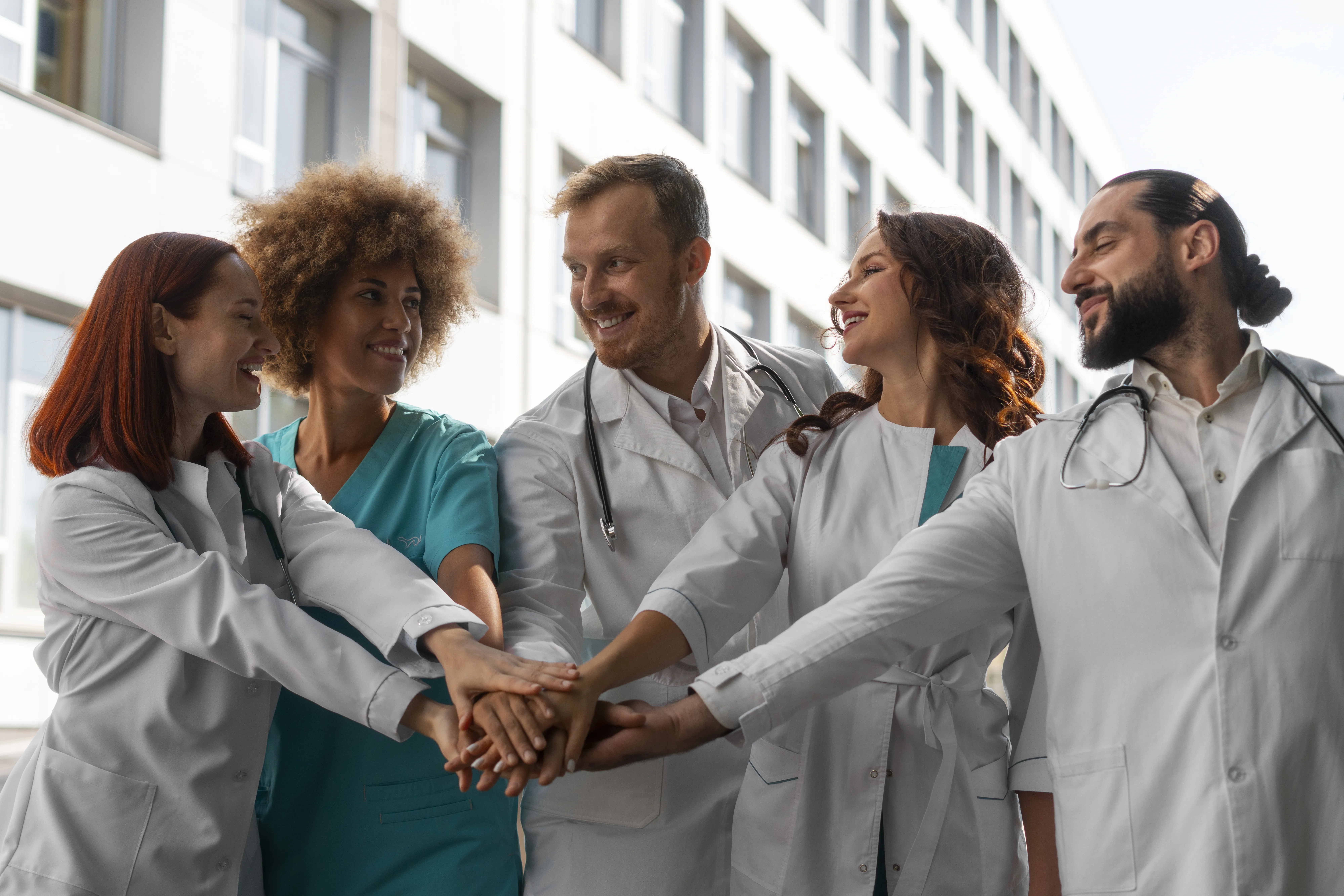 Home 78 Three hospital clinicians in white coats discussing patient care in a modern lobby