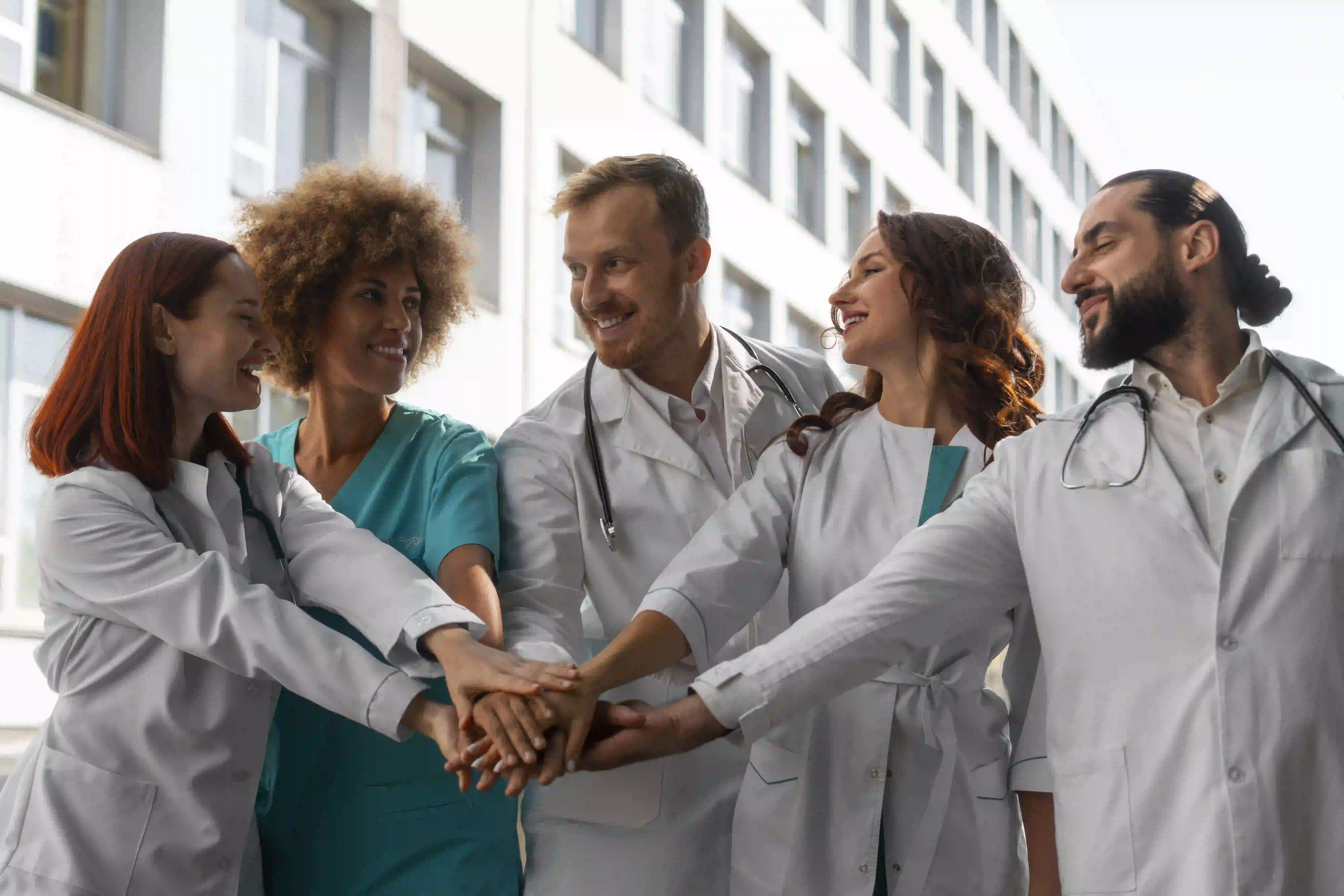 Home 79 Three hospital clinicians in white coats discussing patient care in a modern lobby