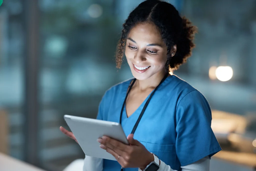 What Is a Wander Management System? 2 Alt text: Nurse in scrubs reviewing patient data on a tablet during a night shift