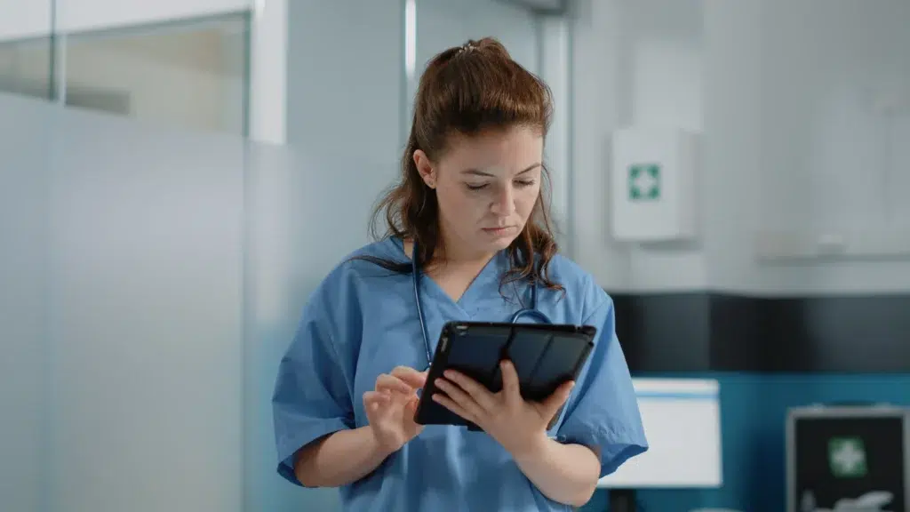 Healthcare Asset Tracking: How Hospitals Use RTLS to Find Equipment Faster 2 Medical assistant using a tablet to check real-time asset tracking information in a hospital ward