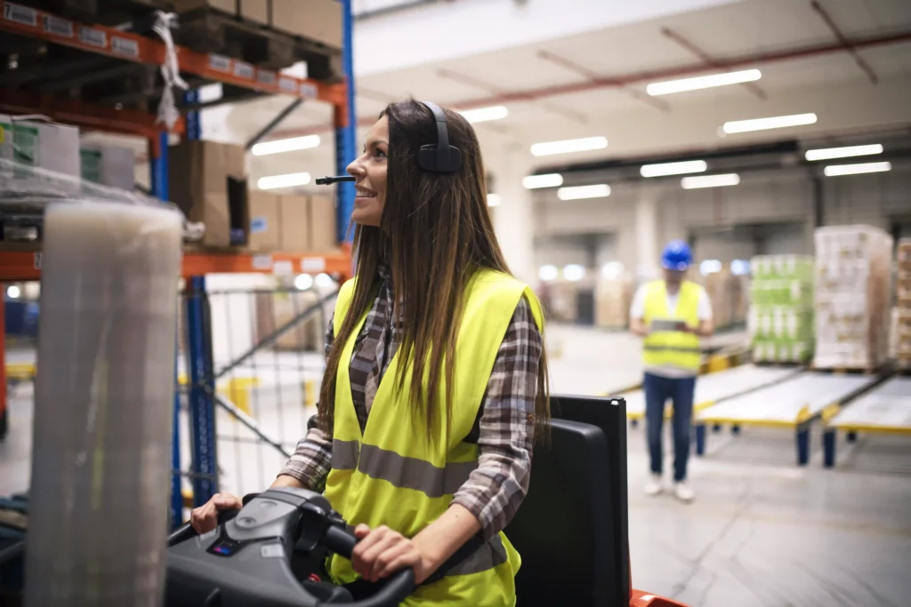 How Does Real-Time Location Tracking Improve Warehouse Safety? 1 Warehouse aisle with forklift and pedestrian workers in a shared space near shelving with limited sightlines