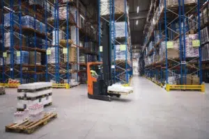 Industrial warehouse interior with forklift and shelves where UWB and BLE RTLS systems are deployed for indoor positioning