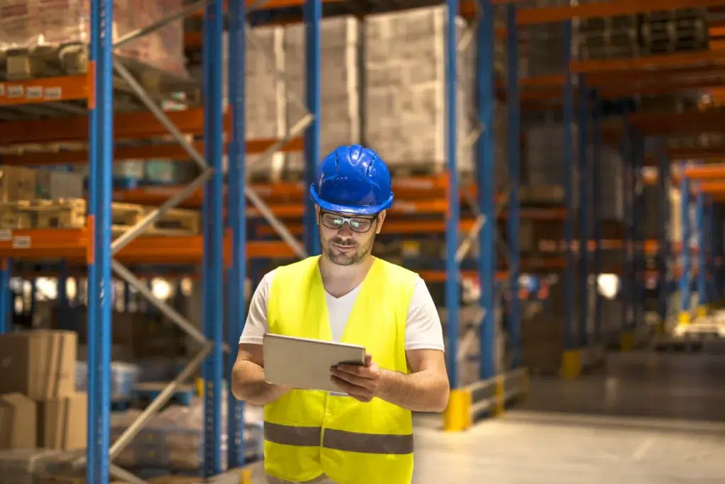 UWB vs BLE for Industrial Tracking: A Practical Decision Guide 2 Warehouse manager using a tablet to monitor real-time location tracking data in a large storage center