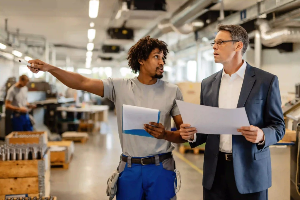 How to Choose an RTLS Vendor: The Industrial Buyer's Guide (2026) 24 Factory manager and team reviewing technology deployment documentation in an industrial facility