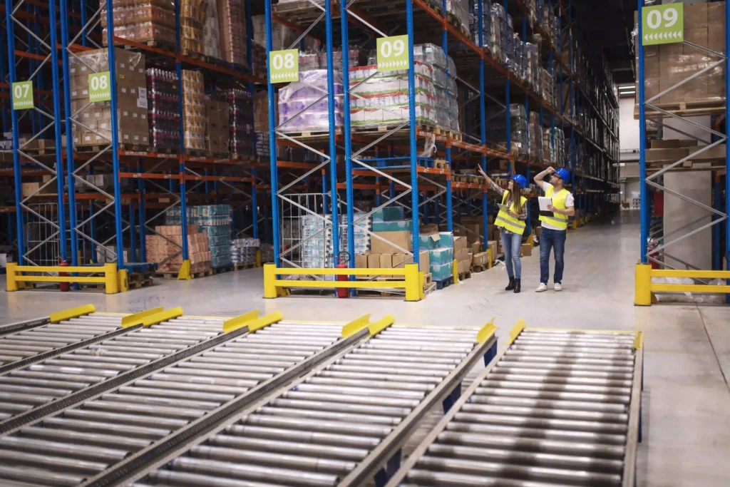 UWB vs BLE for Industrial Tracking: A Practical Decision Guide 3 Warehouse workers checking inventory and distribution in a large storehouse using real-time tracking systems
