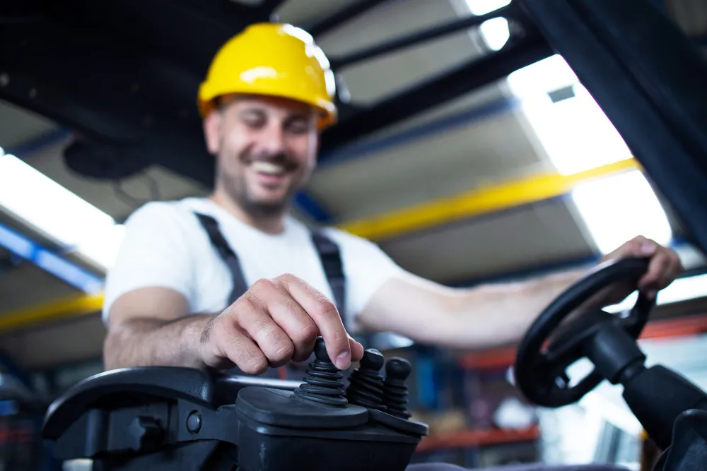 Forklift Safety Systems Differ More Than Their Alerts Suggest 1 Forklift operator adjusting joystick controls while driving in a warehouse
