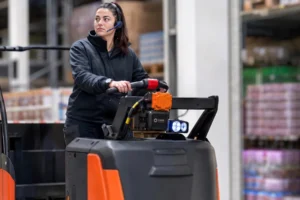 Warehouse operator using a PathAware IQ-equipped tow tractor with mounted safety sensor arm