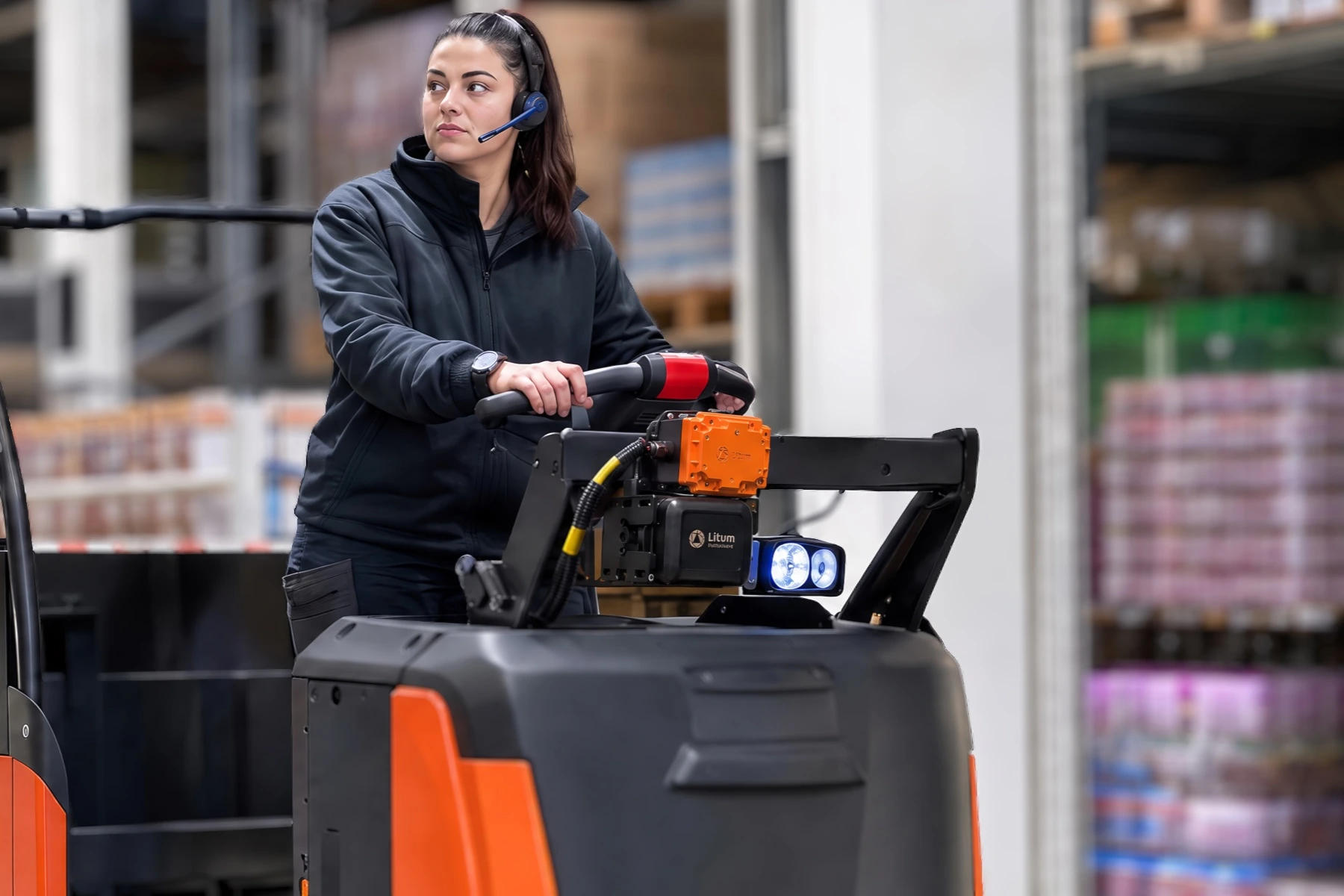 Home 82 Warehouse operator using a PathAware IQ-equipped tow tractor with mounted safety sensor arm