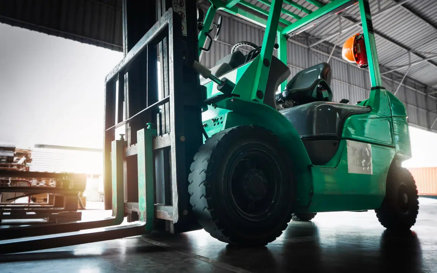 Home 82 Green counterbalance forklift parked at a warehouse loading area with empty forks