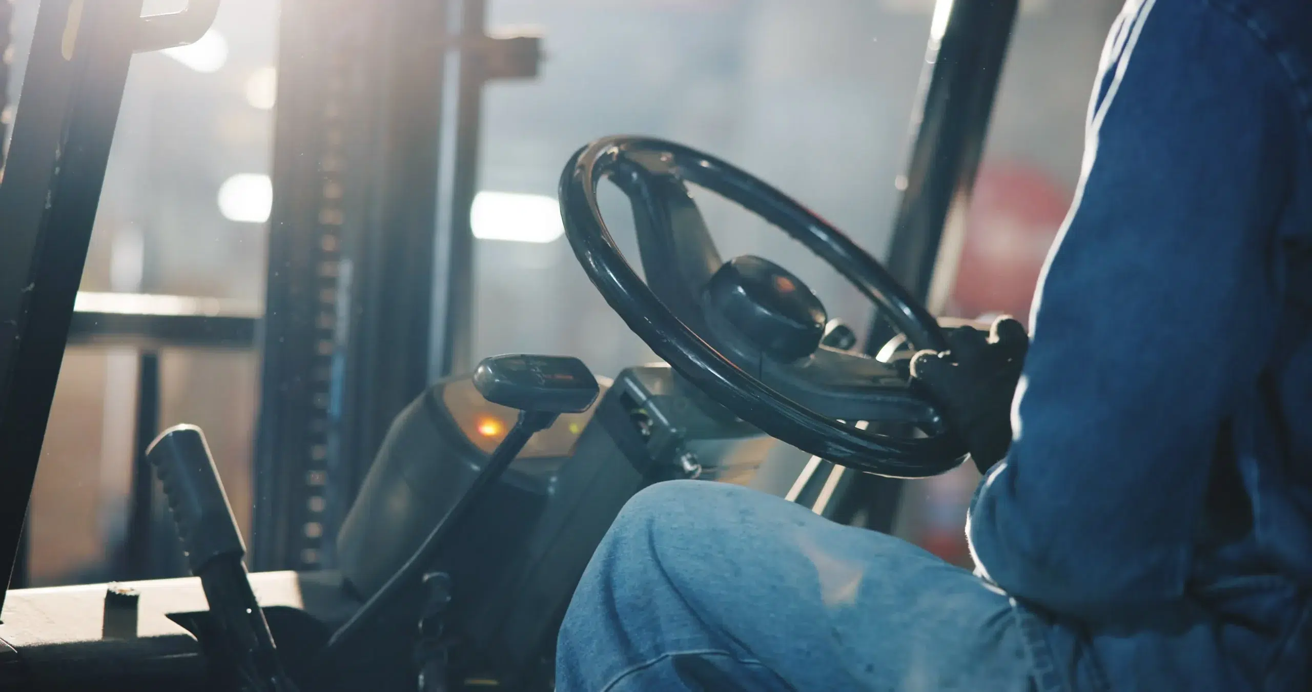 Home 82 Close-up of a forklift operator's hands on the wheel inside the cab
